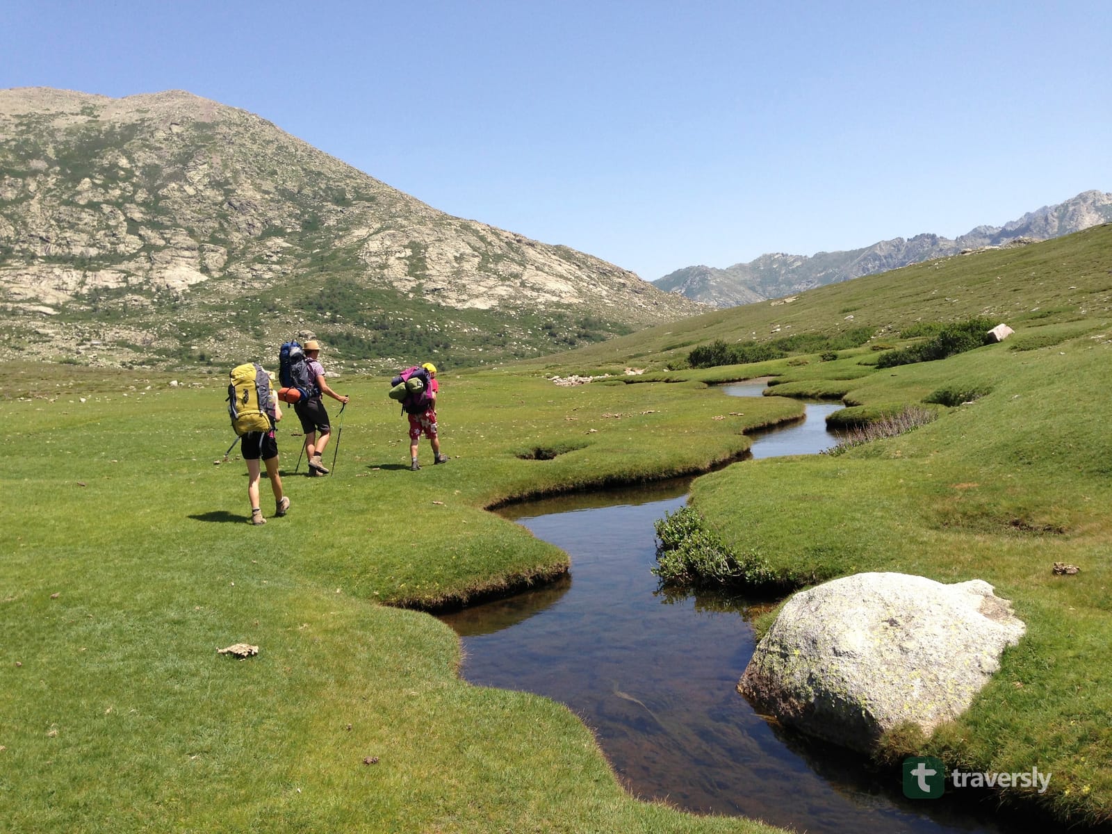 A small mountain stream running over granite slabs, with peaks in the background.